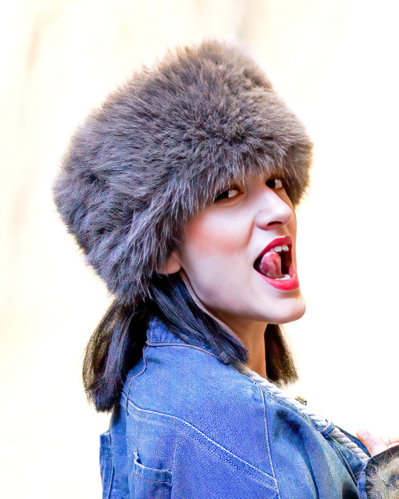 a woman wearing a fur hat and sticking her tongue out